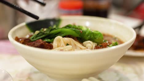 chopsticks lifting noodles from a delicious bowl