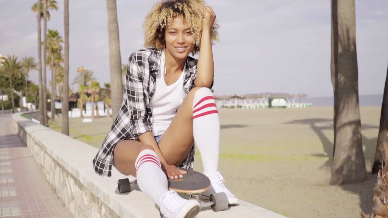Giovane donna pensierosa che si rilassa sul suo skateboard