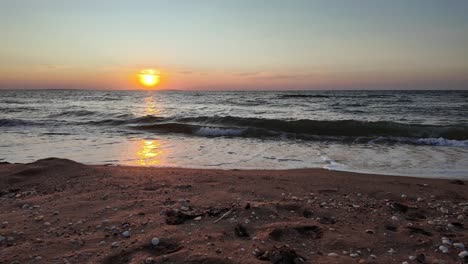 the sun sets beautifully over the sea of azov, casting vibrant colors across the water and illuminating the sandy shoreline