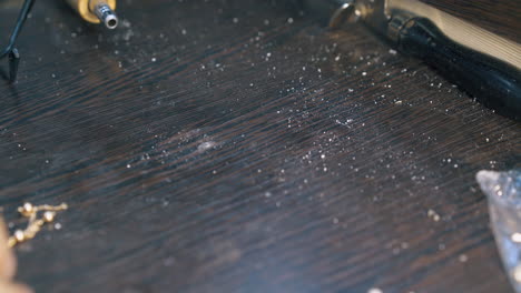 worker takes gold chain from dark table in workshop closeup