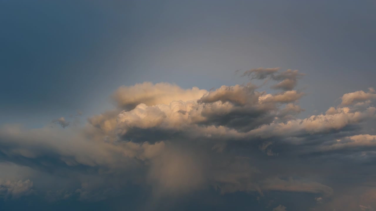 Glowing storm clouds rolling through a richly colored sunset sky scene