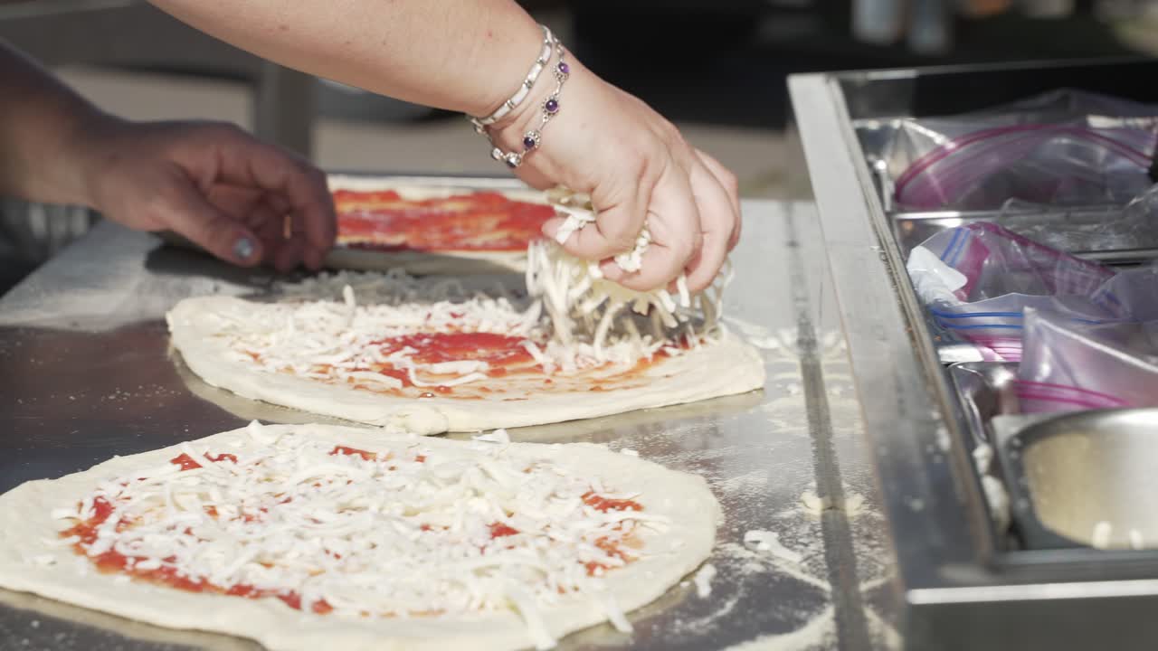 de cerca, las manos de la mujer esparciendo queso mozzarella en masa de pizza fresca en cámara lenta