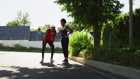 una pareja de ancianos afroamericanos sonrientes haciendo ejercicio al aire libre tomando un descanso