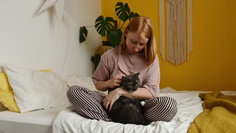 smiling woman embracing fluffy cat in bedroom