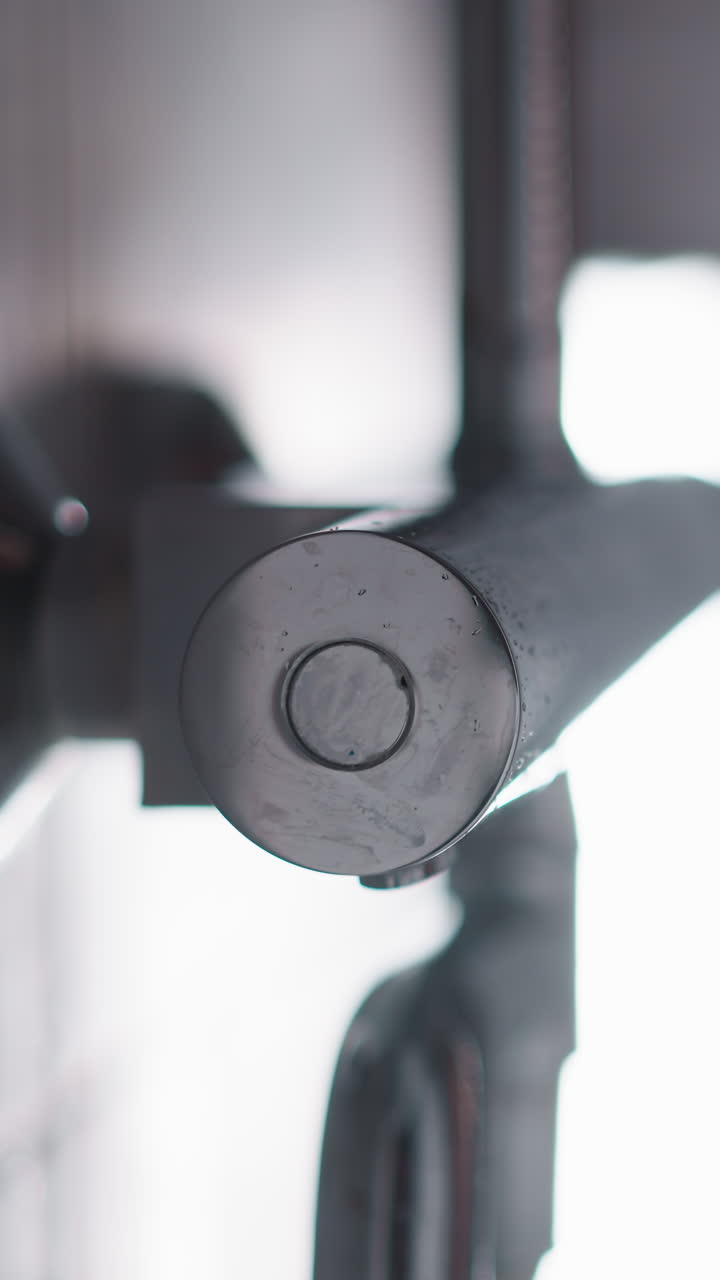 el agua fluye en la ducha ligera bajo buena presión. la ducha de metal plateado proporciona un flujo constante y generoso de agua. el agua fluya en la ducha con pared de azulejos blancos