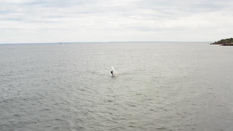 aéreo, persona activa surfeando en el lago superior en un sombrío día nublado