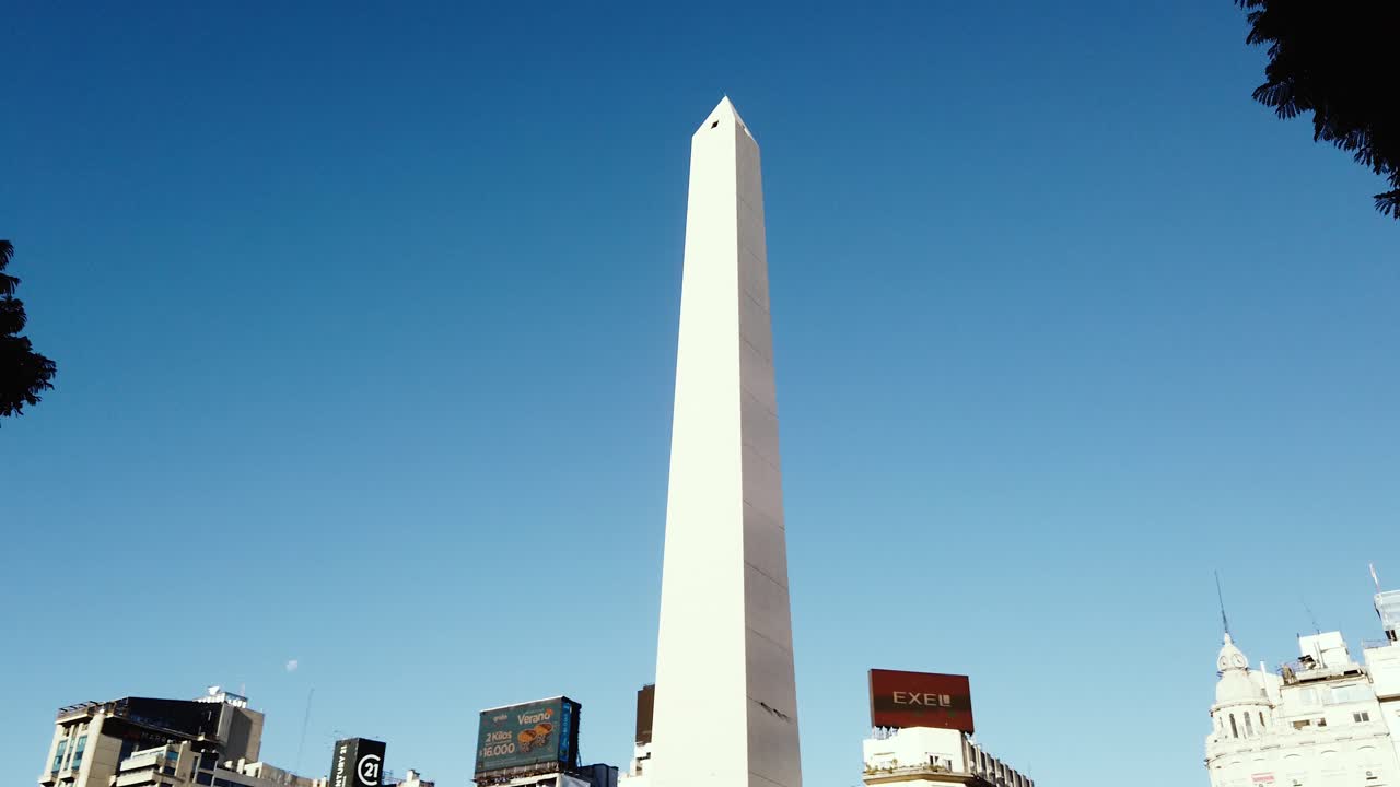 Establishing shot at Obelisk of Buenos Aires city over sunset skyline, commercial billboards, Argentine capital