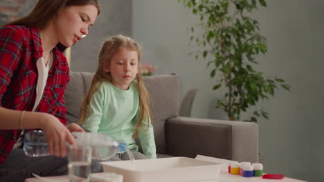 Mädchen-Gießt-Wasser-In-Tablett,-Um-Schwester-Ebru-Zeichnen-Beizubringen