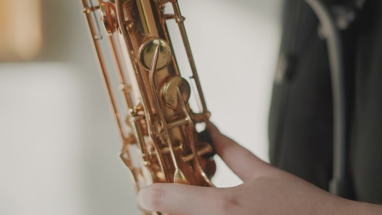 Student plays saxophone. Caucasian pupil actively engaging with saxophone keys during practice. Caucasian student is concentrating on pressing saxophone keys during school practice session