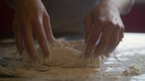 woman's hands making pizza dough on a marble table full of flour