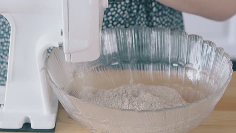 flour pouring out of flour mill into glass bowl slow motion