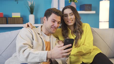 Happy-couple-resting-on-sofa-in-living-room,-having-fun.