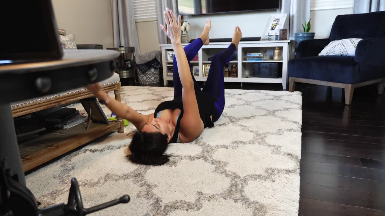 Hispanic female exercising, fitness in home family room, during Coronavirus, sliding reveal view