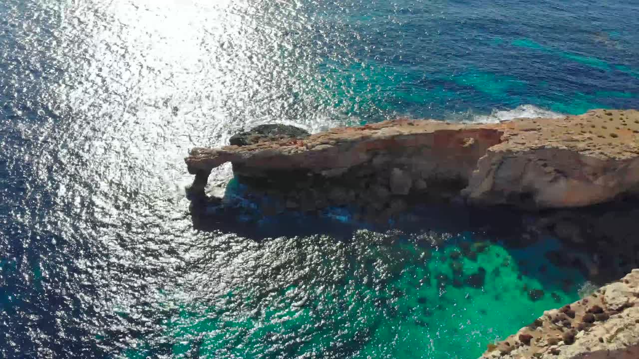 drone disparó sobre rocas en la naturaleza y hacia una ventana de piedra natural en el mar mediterráneo de malta