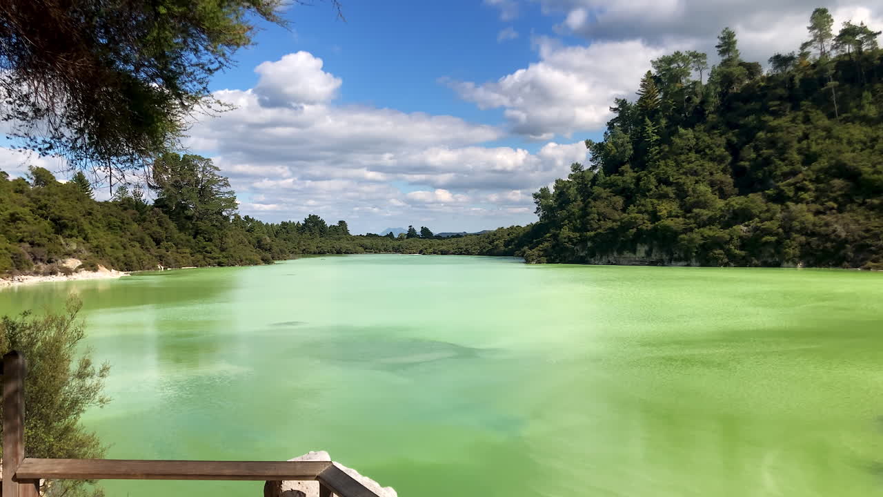 Pan left across the still, green water of Lake Ngakoro in Waiotapu Thermal Wonderland