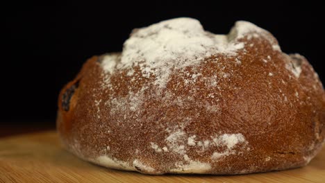 whole loaf of sourdough bread fast rotating on wooden table, isolated on black