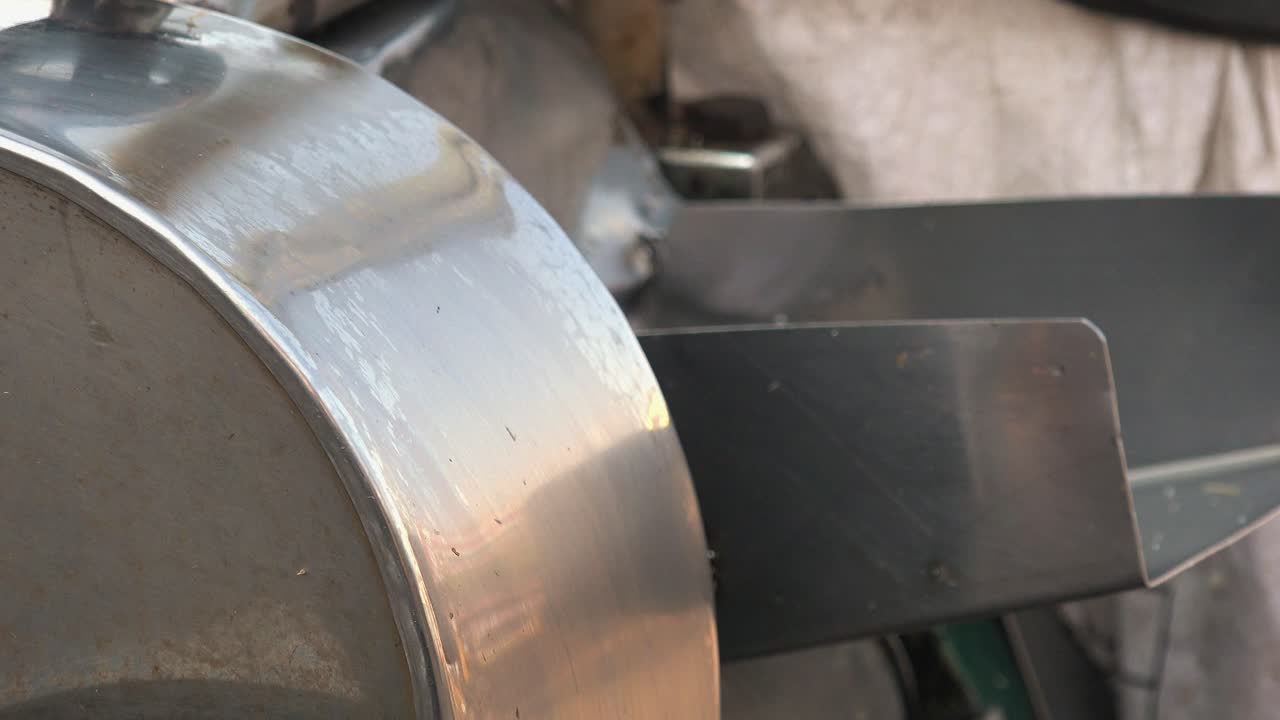 Primo piano di canna da zucchero che passa attraverso uno spremiagrumi su una bancarella del mercato con un macinino di metallo, e poi spremuta una seconda volta