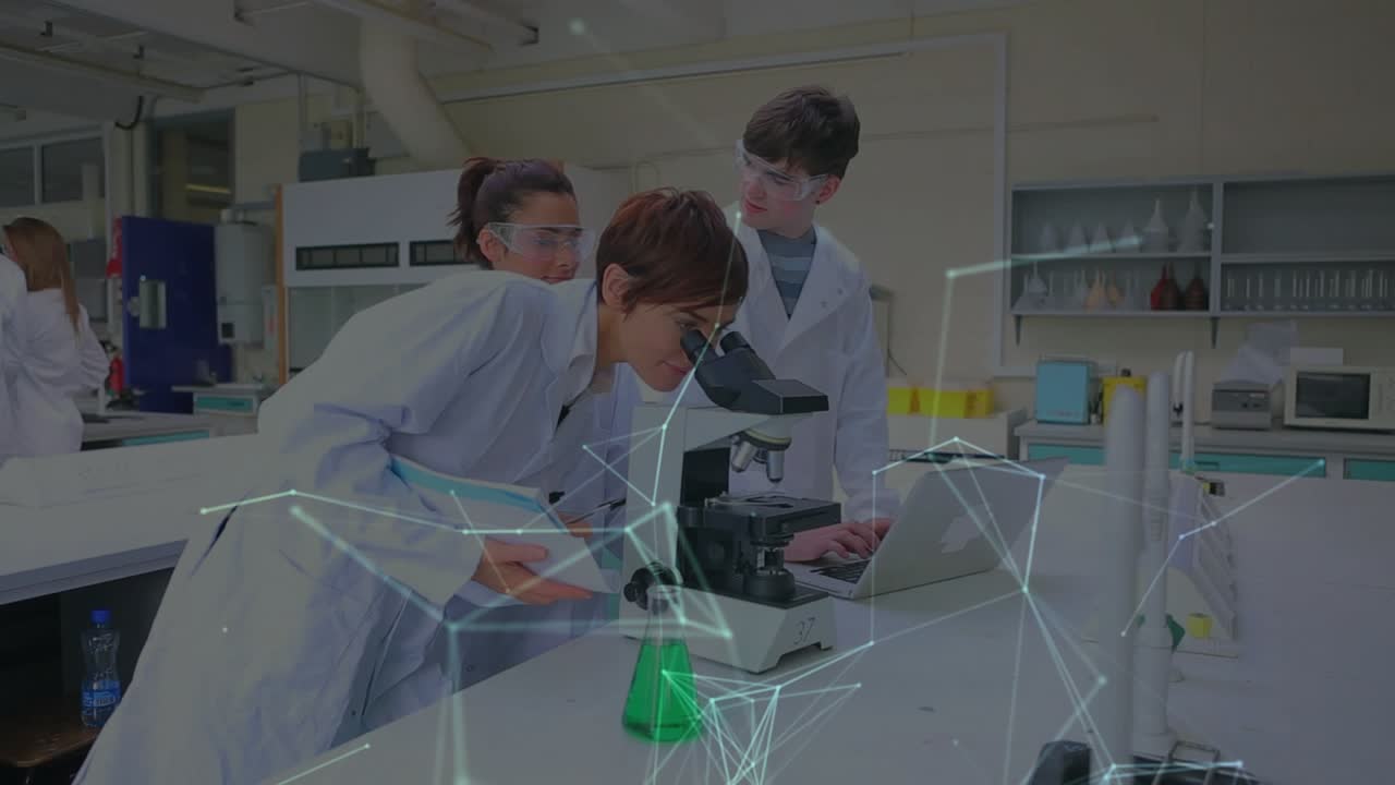 Lab team at scope, lead tech adjusting goggles and peering, causing laptop showing network overlay