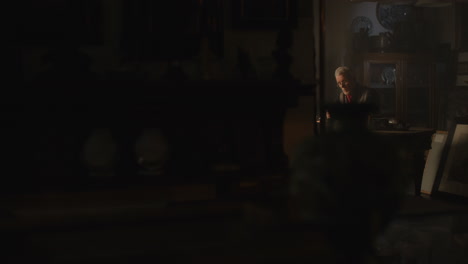older passionate man evaluates an old watch in his office at night