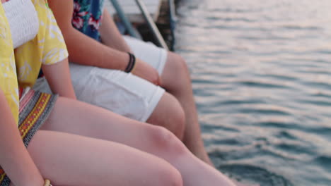 couple sitting on pier and splashing lake water with feet