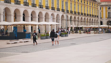 people walking through a lisbon square with outdoor restaurants