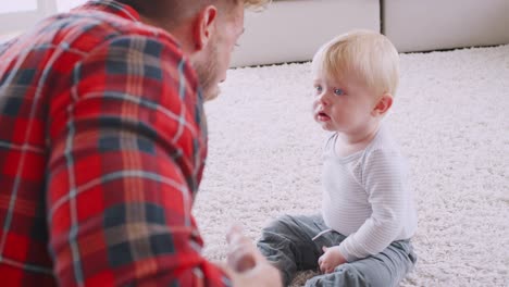 toddler son sits watching his dad play ukulele and sing