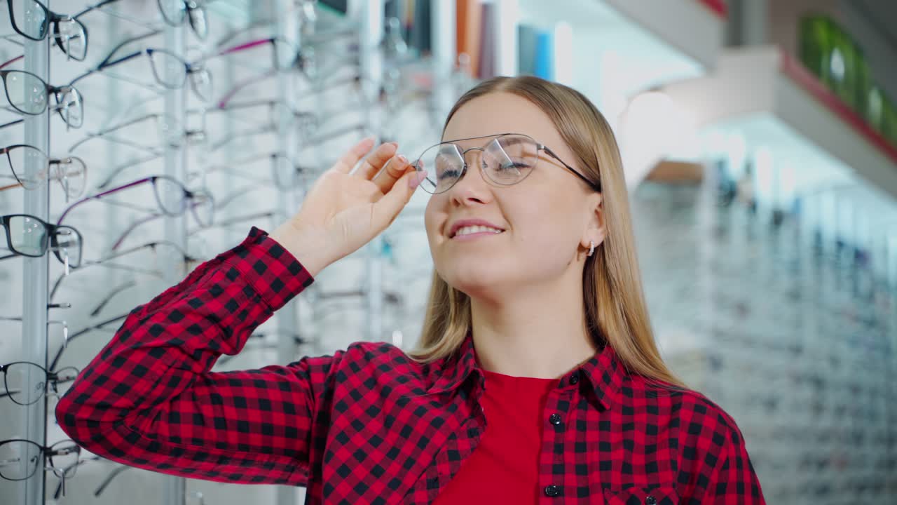 Smiling woman wearing new stylish glasses. Beautiful girl buying eyeglasses in the optical store. Female customer choosing spectacles.