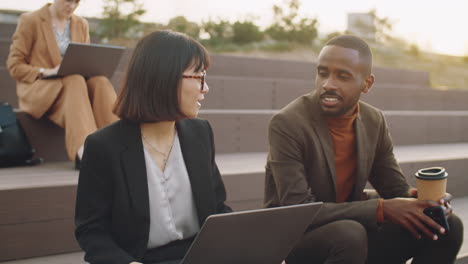 asian woman and black man discussing business outdoors