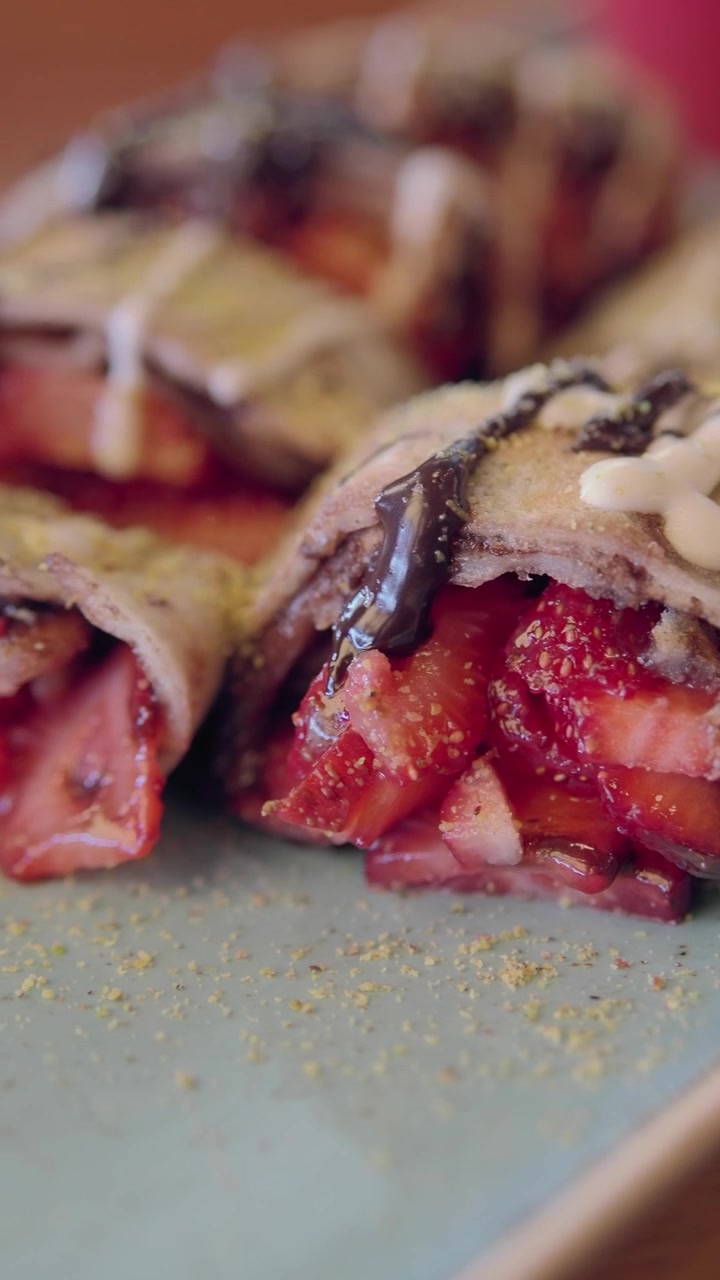 Primo piano di deliziose crepes alle fragole irrorate con salsa al cioccolato