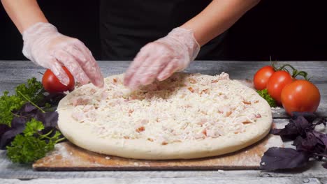 preparing a pizza with ham and cheese