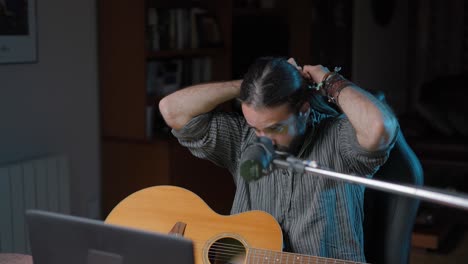 man adjusting hair before recording acoustic guitar session
