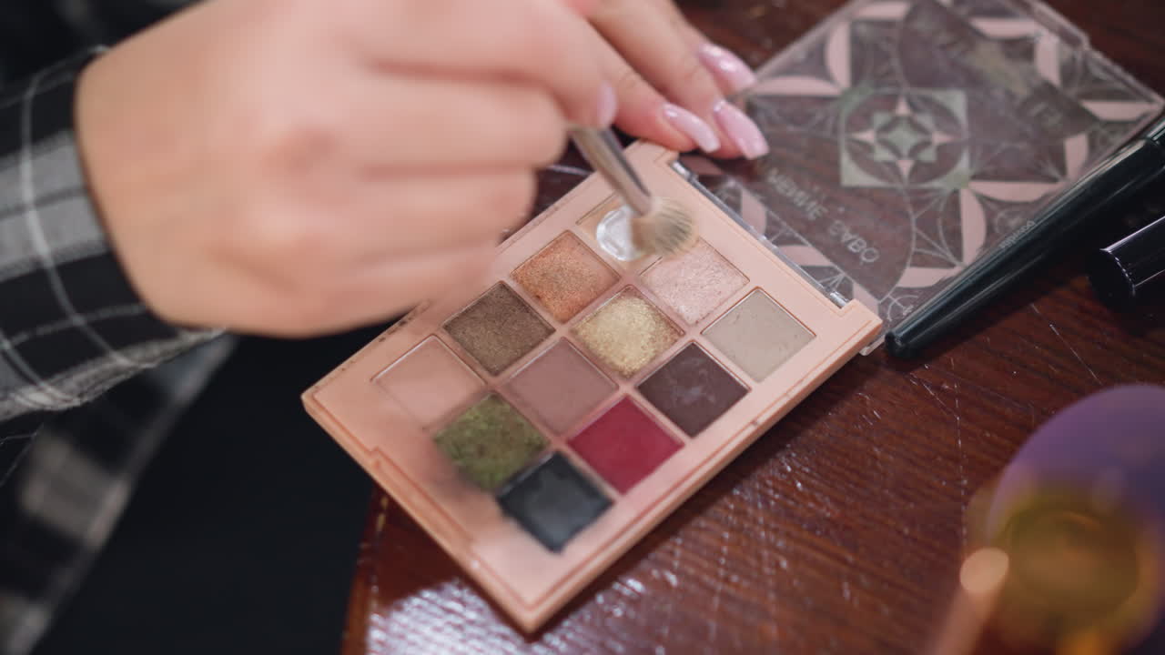 메이크업 패에서 콘투르 파우더를 뽑기 위해 브러쉬를 사용하는 젊은 여자의 손의 클로즈업 뷰, 메이크업 프로세스, 아름다움 및 메이크업 컨셉을 향상시키기 위해 브루쉬에 적용되는 콘투어 파우더