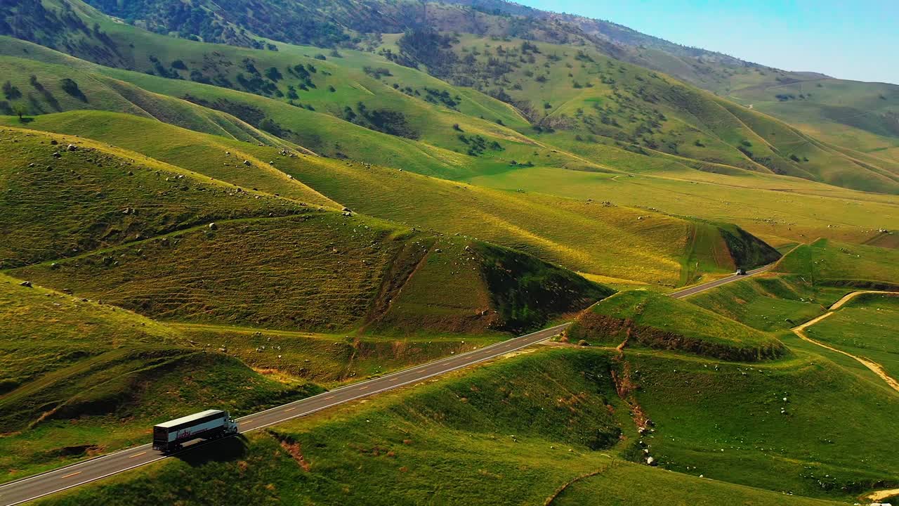 siguiendo un camión de carga a través de las estribaciones de las montañas tehachapi en primavera con un paisaje inusualmente verde - vista aérea de paralaje