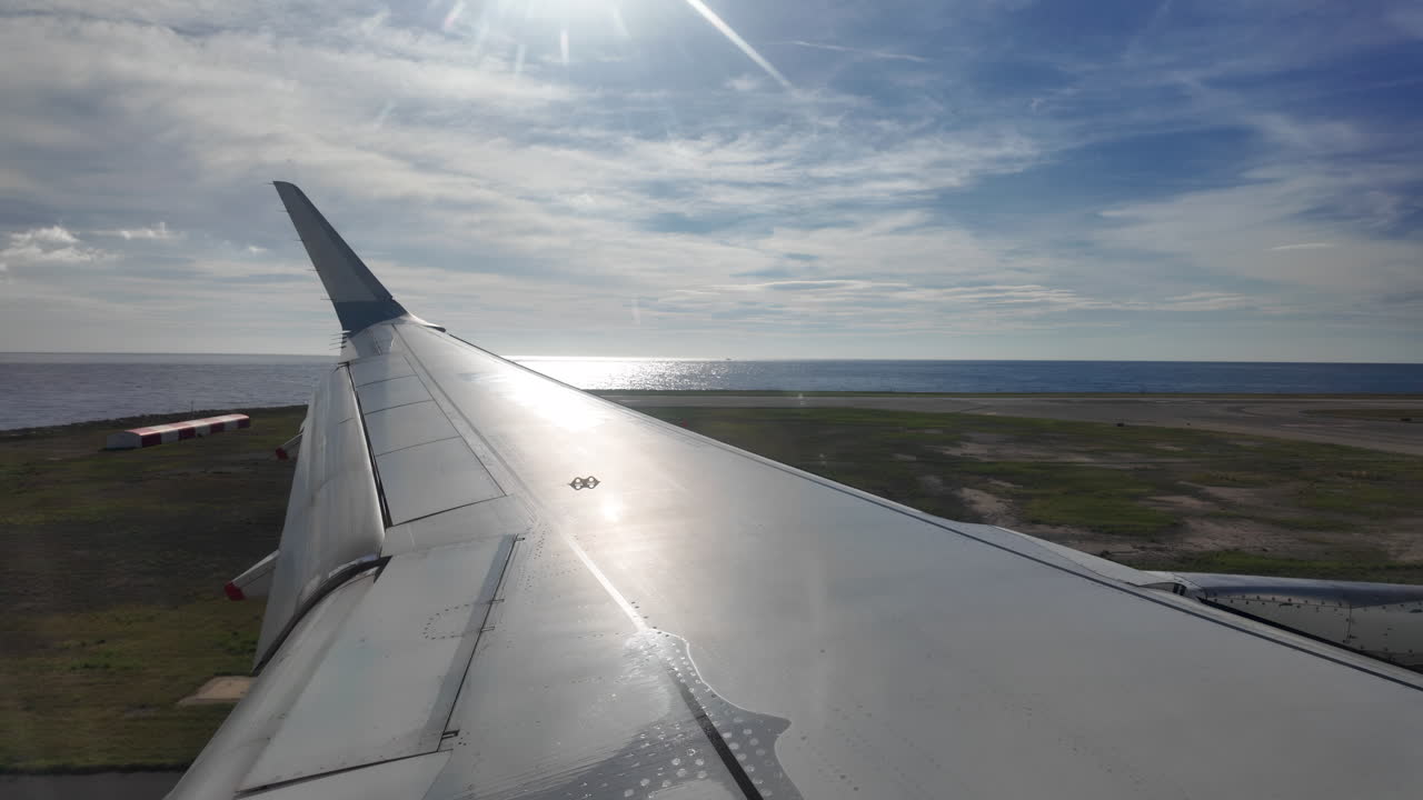 Aircraft wing glides above layered clouds and shimmering sea