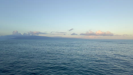 Volando-Sobre-El-Océano-Ondulado-Hacia-La-Silueta-De-La-Isla-Paradisíaca-En-El-Horizonte