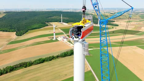 grúa sobre orugas y técnicos en el trabajo de montaje de la góndola de la turbina eólica en el parque eólico