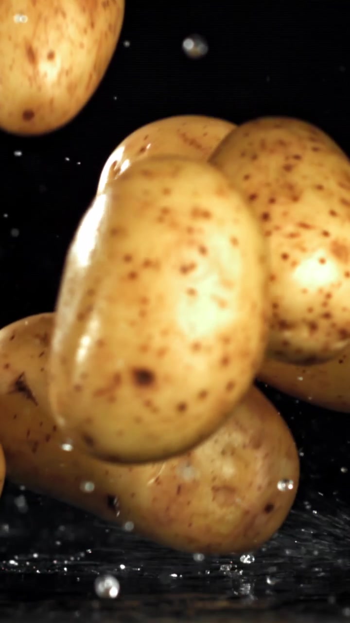 Patate fresche che cadono nell'acqua con schizzi, al rallentatore