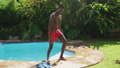 Handsome-african-american-man-walking-out-of-in-swimming-pool-in-sunny-garden