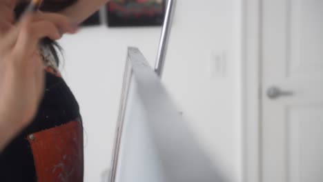 artista femenina sosteniendo un pincel pintando el costado del lienzo