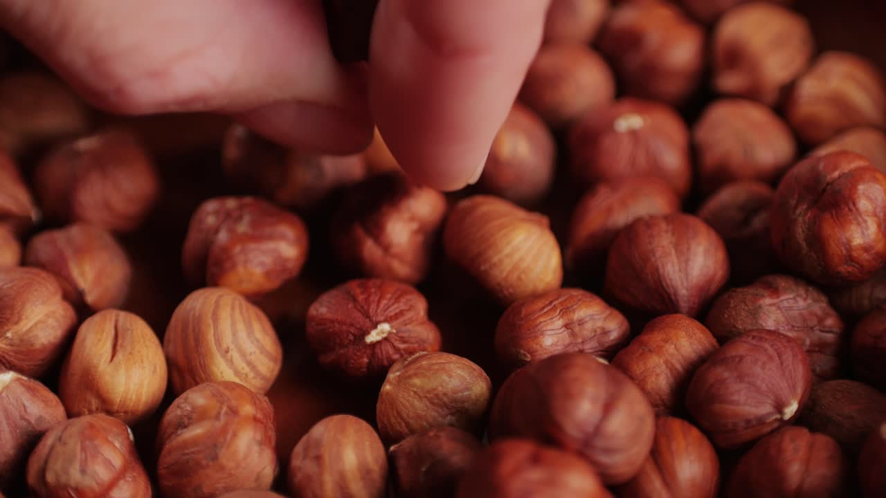 Peeled hazelnut on red plate close-up macro. Hazelnuts without shell. Man hand take some nuts. Product rich in minerals and vitamins. Healthy snacks.High quality 4k footage