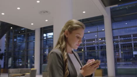 mujer de negocios usando teléfono móvil en el vestíbulo de la oficina 4k
