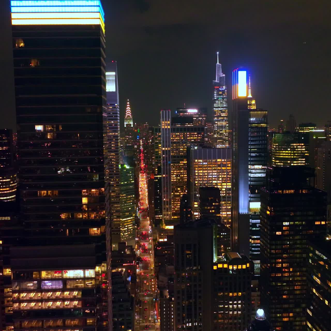 Impressive scenery of sparkling New York at nighttime. Skyscraper's tops lit in blue and yellow colors to support Ukraine. Top view