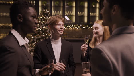 group friends wearing stylish clothes while talking and toasting with champagne glasses at new year's party 1