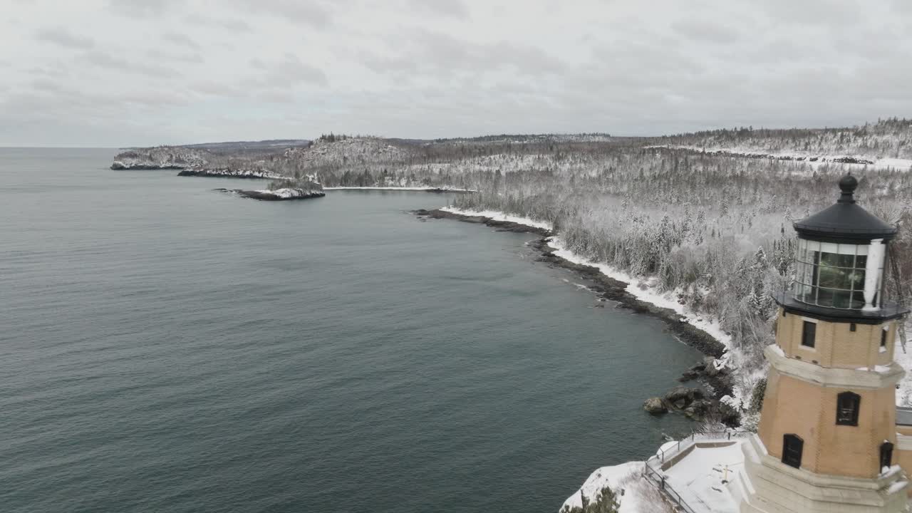 Split Rock Lighthouse And Icy Forest Landscape On Shore Of Lake Superior In Winter. Minnesota, USA. wide drone shot