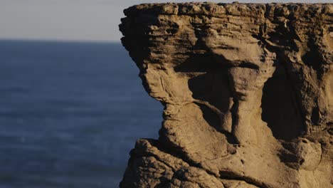 Cliff-or-rock-and-blue-ocean-water-in-background,-copyspace-for-titles,-stable-view