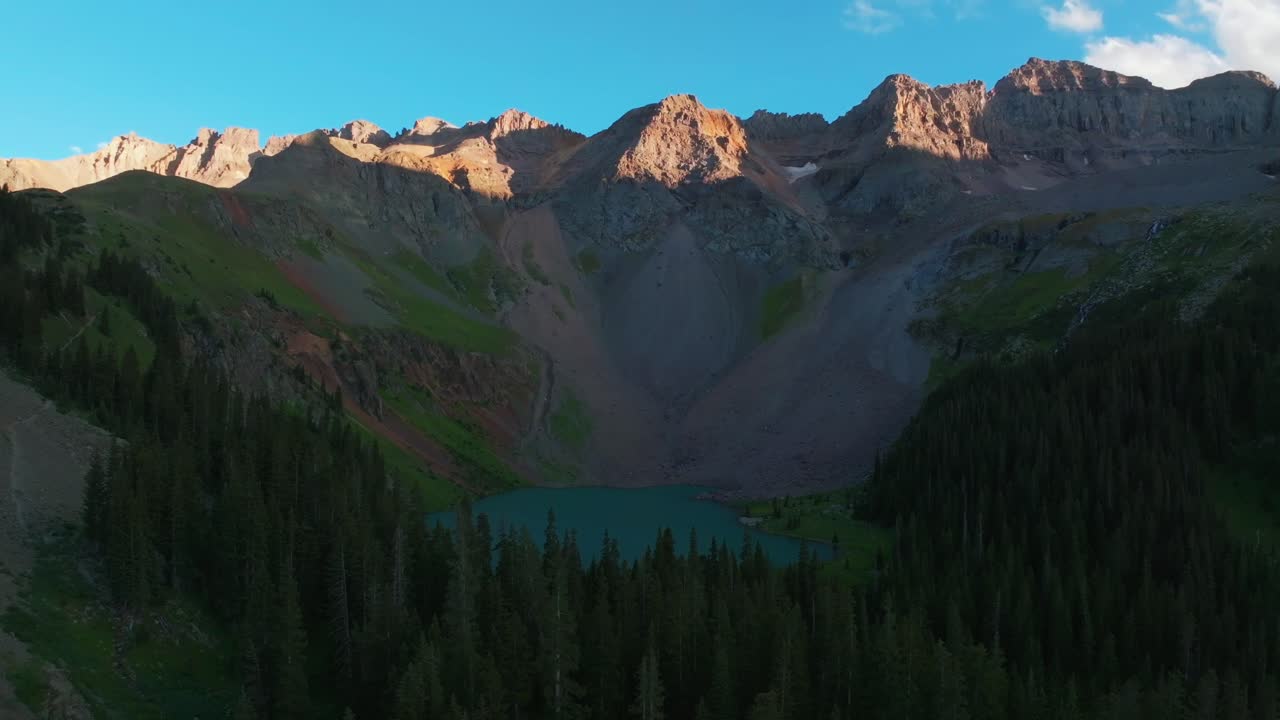 Sunset dusk Lower Blue Lake Mount Sneffels Wilderness Ridgway Telluride Colorado aerial drone golden hour shaded peaks San Juan Rocky Mountains Uncompahgre National Forest blue sky forward pan up