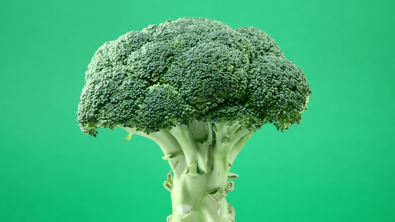 Fresh raw broccoli rotating over green background