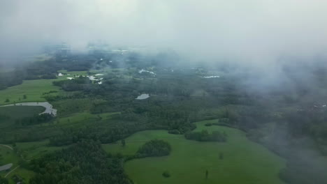 Aerial-drone-shot-of-beautiful-green-rural-landscape-through-white-clouds-at-daytime