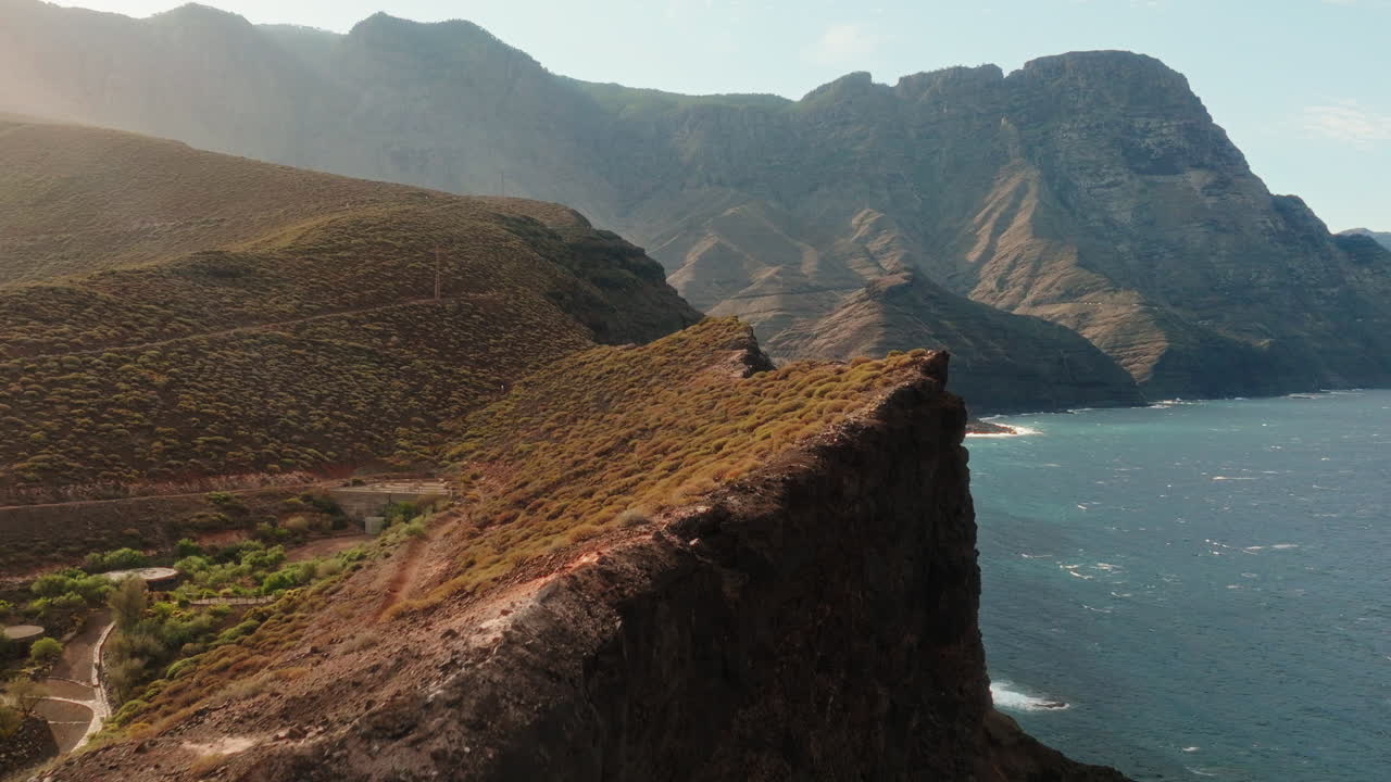 Mot6ion video over hill top during afternoon with arid hills and mountains at background in Gran Canaria, Spain.