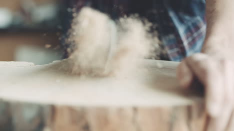 carpenter cutting wood with handsaw in workshop 11